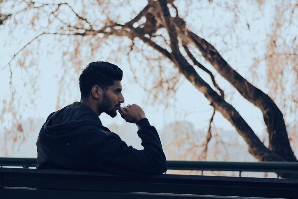 Man sitting on a bench outdoors, deep in thought about life decisions